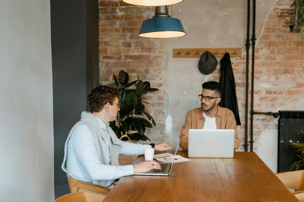 Two men having a conversation in front of a laptop